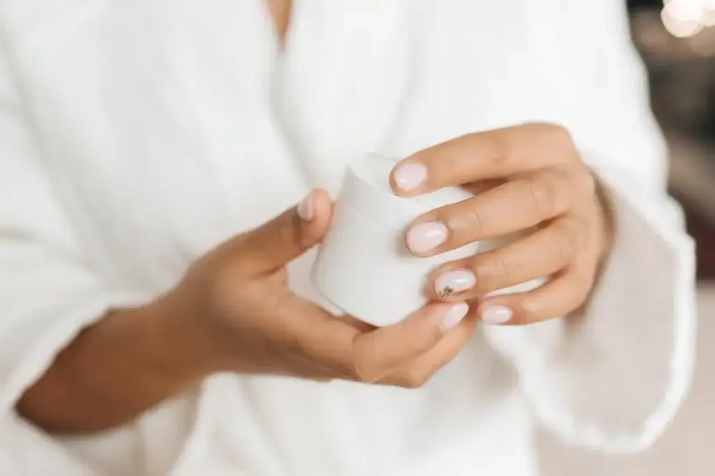 Hands holding a skincare cream jar representing moisturizing and nourishing skin care routine