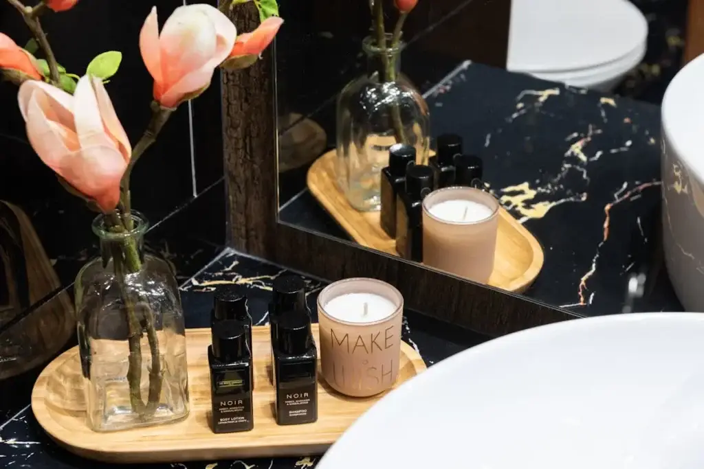 Luxury skincare products and candle displayed beside a sink with flowers creating a relaxing spa environment